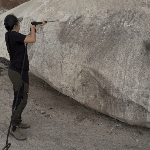 Miriam Diddy pressure washes graffiti of the chip at Giant Rock